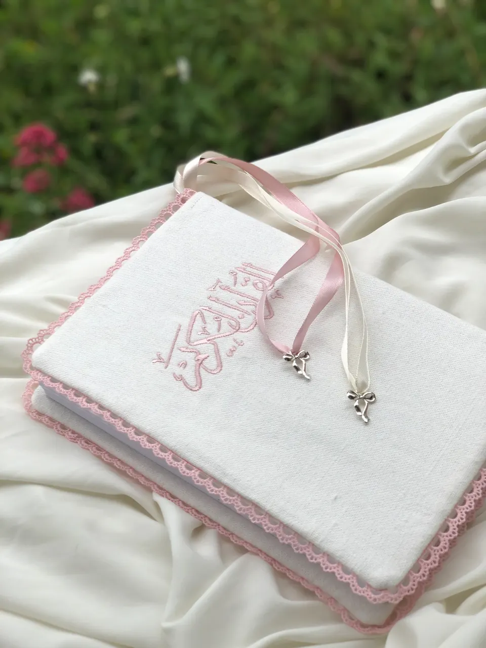 White cotton book cover, Al-Quran Al-Karim calligraphy embroidered in powder pink, pink crown lace, pink and cream ribbons with silver bows
