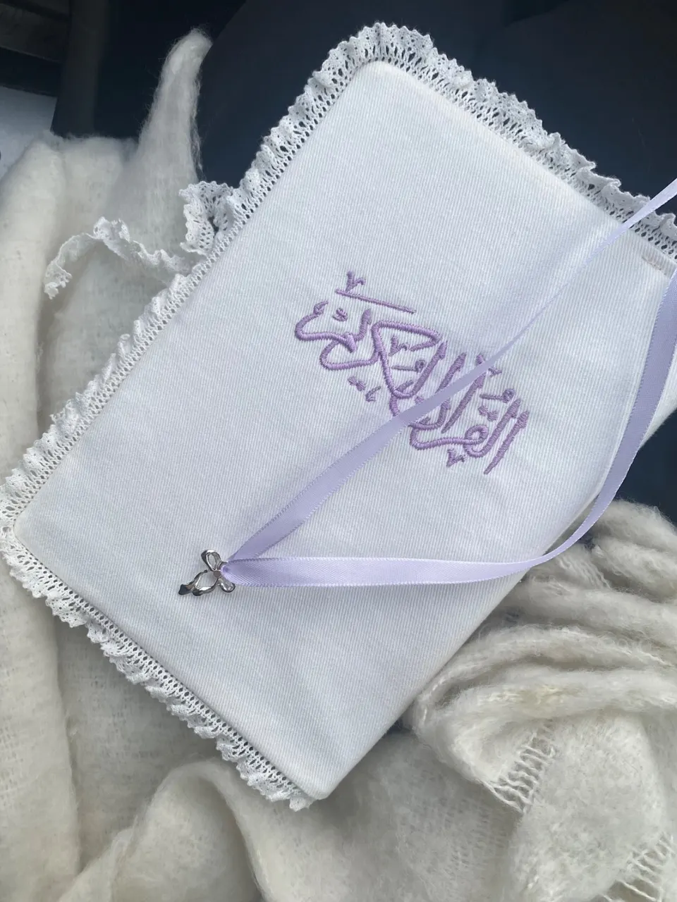 White cotton book cover, Al-Quran Al-Karim calligraphy embroidered in lilac, white macramé lace, lilac ribbon with a silver bow charm