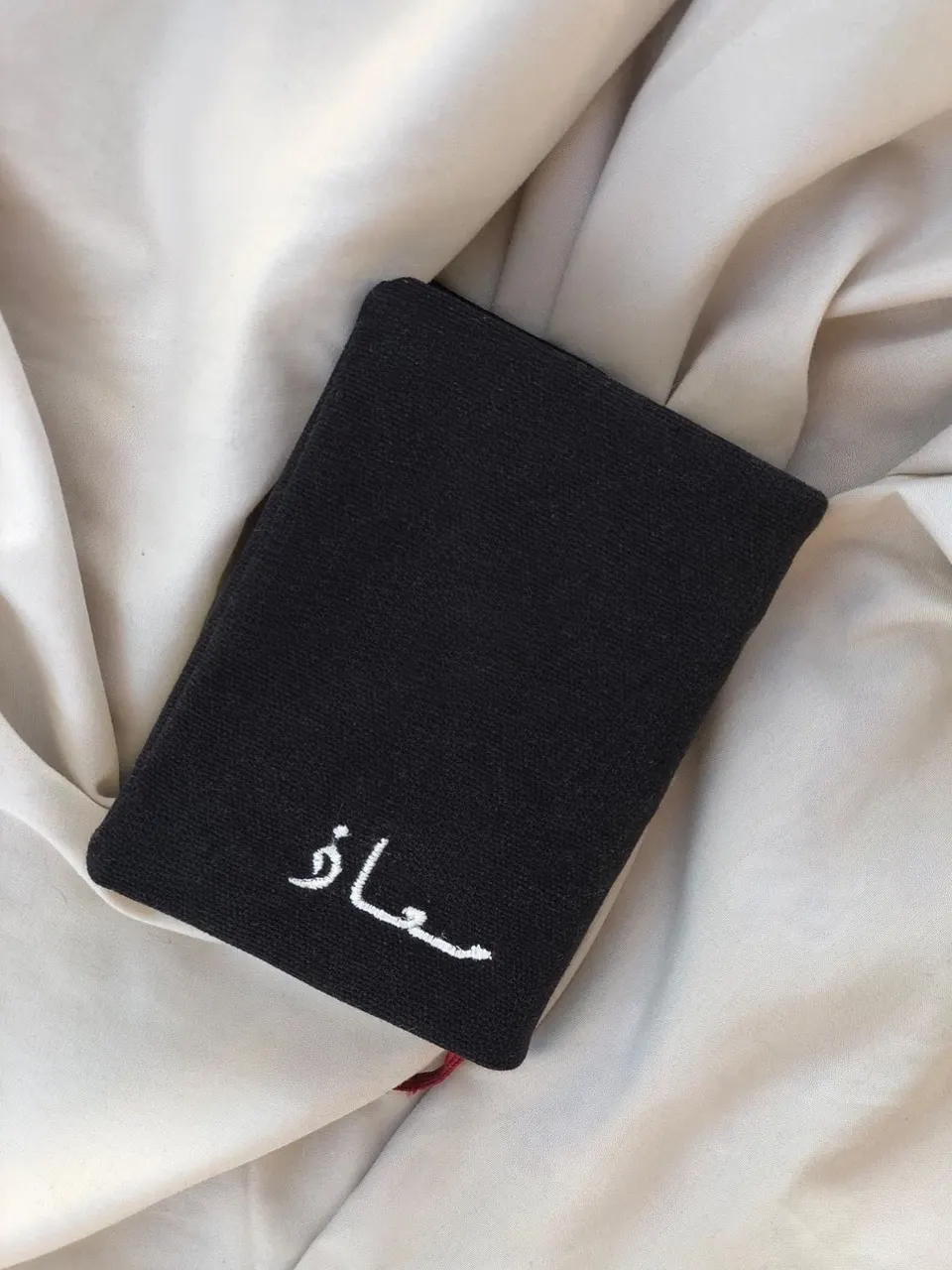 Small black cotton book cover, Arabic name calligraphy embroidered in white thread, understated style